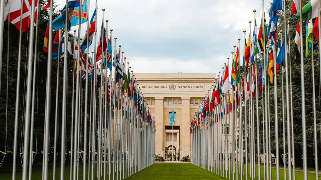 many flags are flying in the air in front of a building