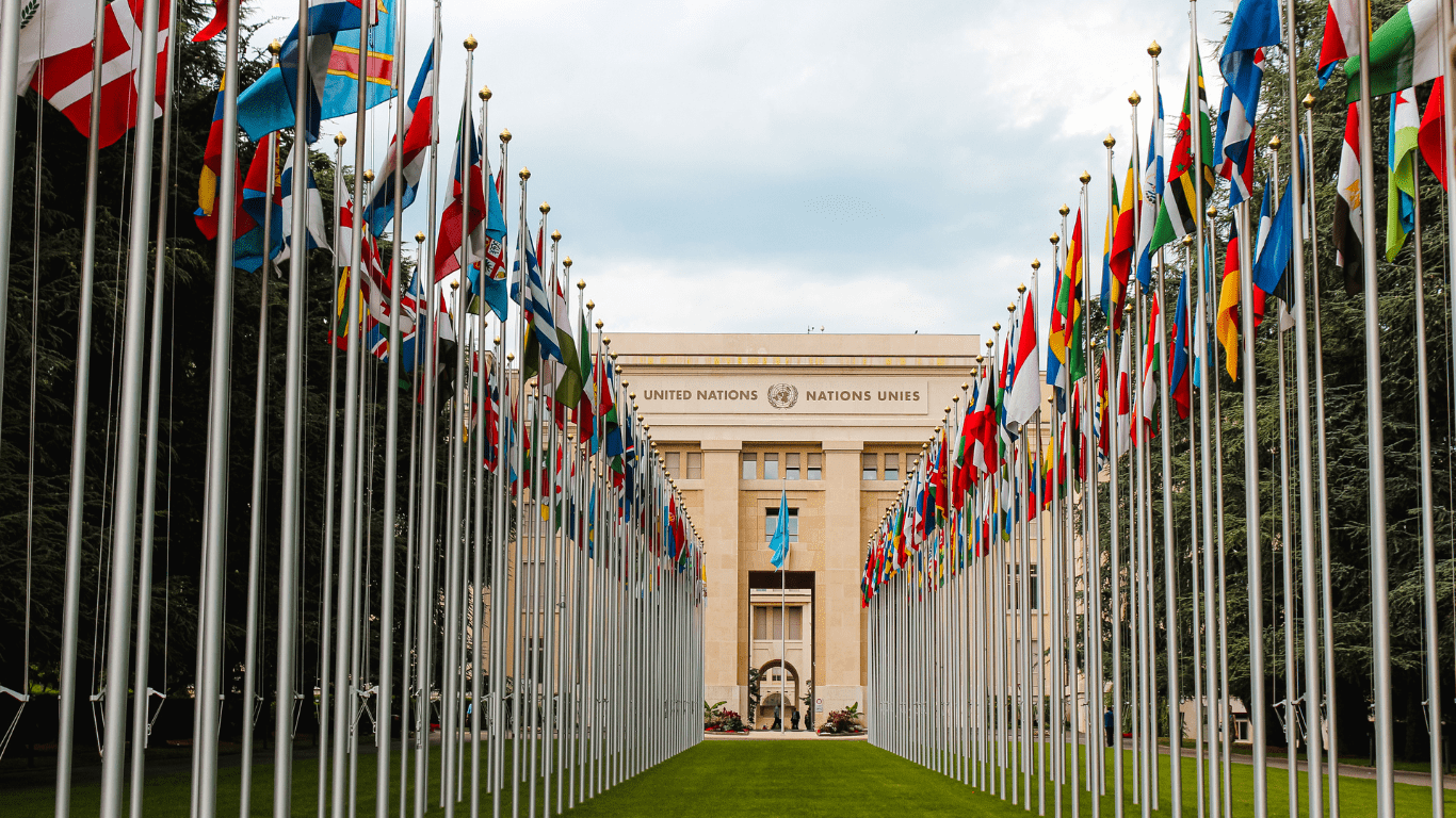 many flags are flying in the air in front of a building