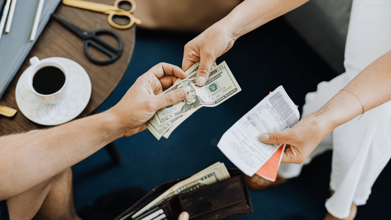 a person handing money to another person at a desk