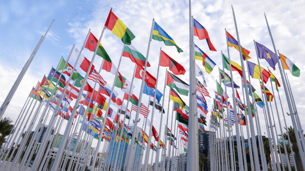 many flags are flying in the air in front of a building